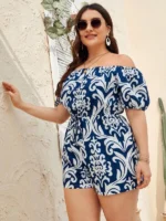 Macaquinho Plus Size Barroco Yasmin, com gola ombro a ombro e estampa azul e branca. Casual, elegante e ideal para diversas ocasiões.