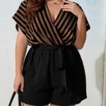 Macaquinho Plus Size Listrado Pâmela, com manga morcego, decote V, cinto e estampa listrada. Versátil, leve e estiloso para qualquer ocasião.