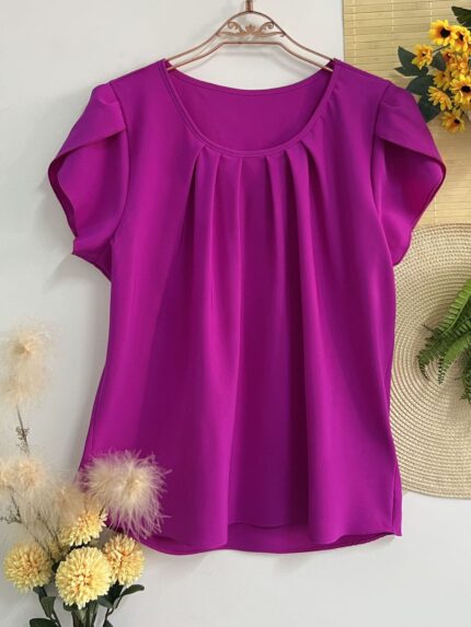 Blusa Plus Size Laís em rosê, com mangas curtas de pétala, gola redonda, bainha flared e detalhes dobrados. Confortável e elegante para o dia a dia.