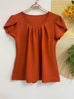 Blusa Plus Size Laís em rosê, com mangas curtas de pétala, gola redonda, bainha flared e detalhes dobrados. Confortável e elegante para o dia a dia.