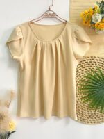 Blusa Plus Size Laís em rosê, com mangas curtas de pétala, gola redonda, bainha flared e detalhes dobrados. Confortável e elegante para o dia a dia.