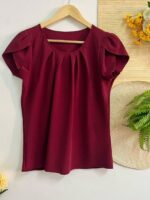 Blusa Plus Size Laís em rosê, com mangas curtas de pétala, gola redonda, bainha flared e detalhes dobrados. Confortável e elegante para o dia a dia.