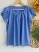 Blusa Plus Size Laís em rosê, com mangas curtas de pétala, gola redonda, bainha flared e detalhes dobrados. Confortável e elegante para o dia a dia.