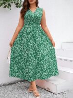 Vestido Plus Size Carla, boho, com estampa de plantas e flores em fundo preto, cintura alta, decote V, detalhes cruzados e franzidos.
