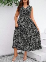 Vestido Plus Size Carla, boho, com estampa de plantas e flores em fundo preto, cintura alta, decote V, detalhes cruzados e franzidos.