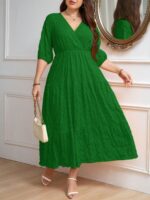 Vestido Plus Size Amanda em rosa chiclete, design em A, cintura alta, mangas bishop, decote V, babados esvoaçantes e detalhes cruzados.