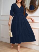 Vestido Plus Size Amanda em rosa chiclete, design em A, cintura alta, mangas bishop, decote V, babados esvoaçantes e detalhes cruzados.