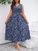 Vestido Plus Size Carla, boho, com estampa de plantas e flores em fundo preto, cintura alta, decote V, detalhes cruzados e franzidos.