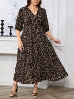 Vestido Plus Size Amanda em rosa chiclete, design em A, cintura alta, mangas bishop, decote V, babados esvoaçantes e detalhes cruzados.