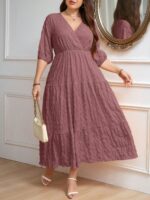 Vestido Plus Size Amanda em rosa chiclete, design em A, cintura alta, mangas bishop, decote V, babados esvoaçantes e detalhes cruzados.