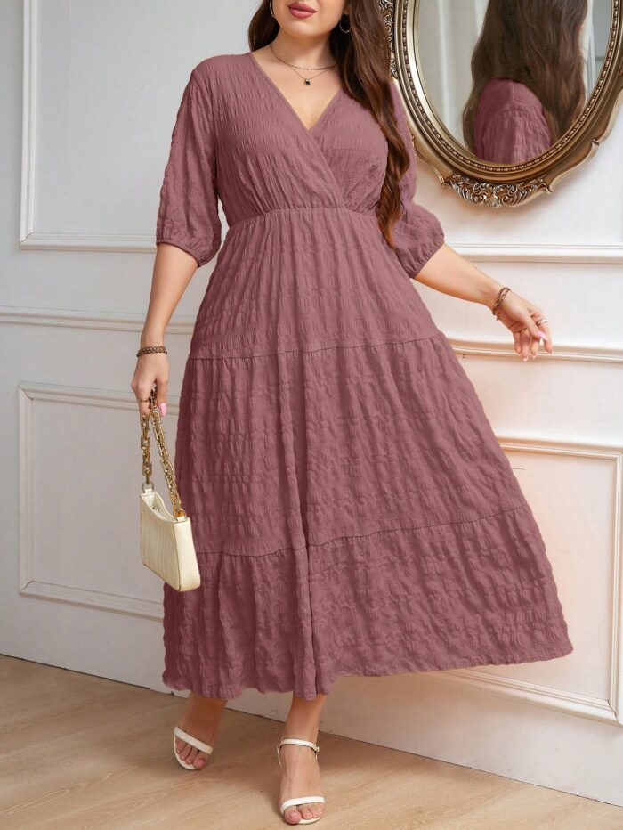 Vestido Plus Size Amanda em rosa chiclete, design em A, cintura alta, mangas bishop, decote V, babados esvoaçantes e detalhes cruzados.