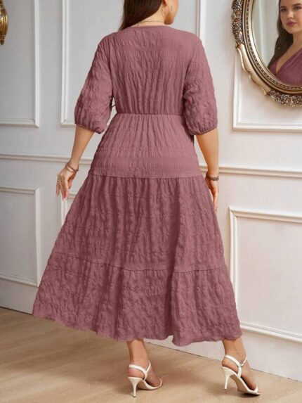 Vestido Plus Size Amanda em rosa chiclete, design em A, cintura alta, mangas bishop, decote V, babados esvoaçantes e detalhes cruzados.
