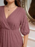 Vestido Plus Size Amanda em rosa chiclete, design em A, cintura alta, mangas bishop, decote V, babados esvoaçantes e detalhes cruzados.