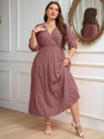 Vestido Plus Size Amanda em rosa chiclete, design em A, cintura alta, mangas bishop, decote V, babados esvoaçantes e detalhes cruzados.