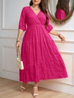 Vestido Plus Size Amanda em rosa chiclete, design em A, cintura alta, mangas bishop, decote V, babados esvoaçantes e detalhes cruzados.