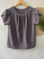 Blusa Plus Size Laís em rosê, com mangas curtas de pétala, gola redonda, bainha flared e detalhes dobrados. Confortável e elegante para o dia a dia.