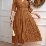 Vestido Plus Size Amanda em rosa chiclete, design em A, cintura alta, mangas bishop, decote V, babados esvoaçantes e detalhes cruzados.