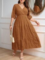 Vestido Plus Size Amanda em rosa chiclete, design em A, cintura alta, mangas bishop, decote V, babados esvoaçantes e detalhes cruzados.