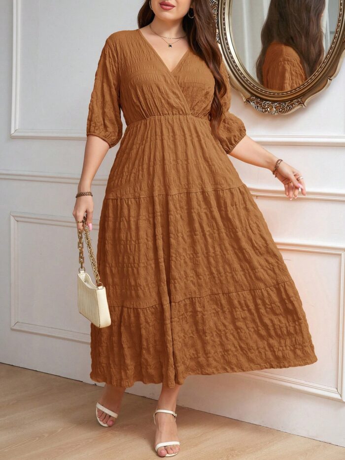 Vestido Plus Size Amanda em rosa chiclete, design em A, cintura alta, mangas bishop, decote V, babados esvoaçantes e detalhes cruzados.