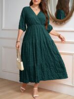 Vestido Plus Size Amanda em rosa chiclete, design em A, cintura alta, mangas bishop, decote V, babados esvoaçantes e detalhes cruzados.