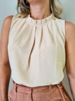 Blusa feminina regata amarela, sem mangas, com gola redonda e detalhes de botão. Leve e elegante, ideal para um visual casual e sofisticado.